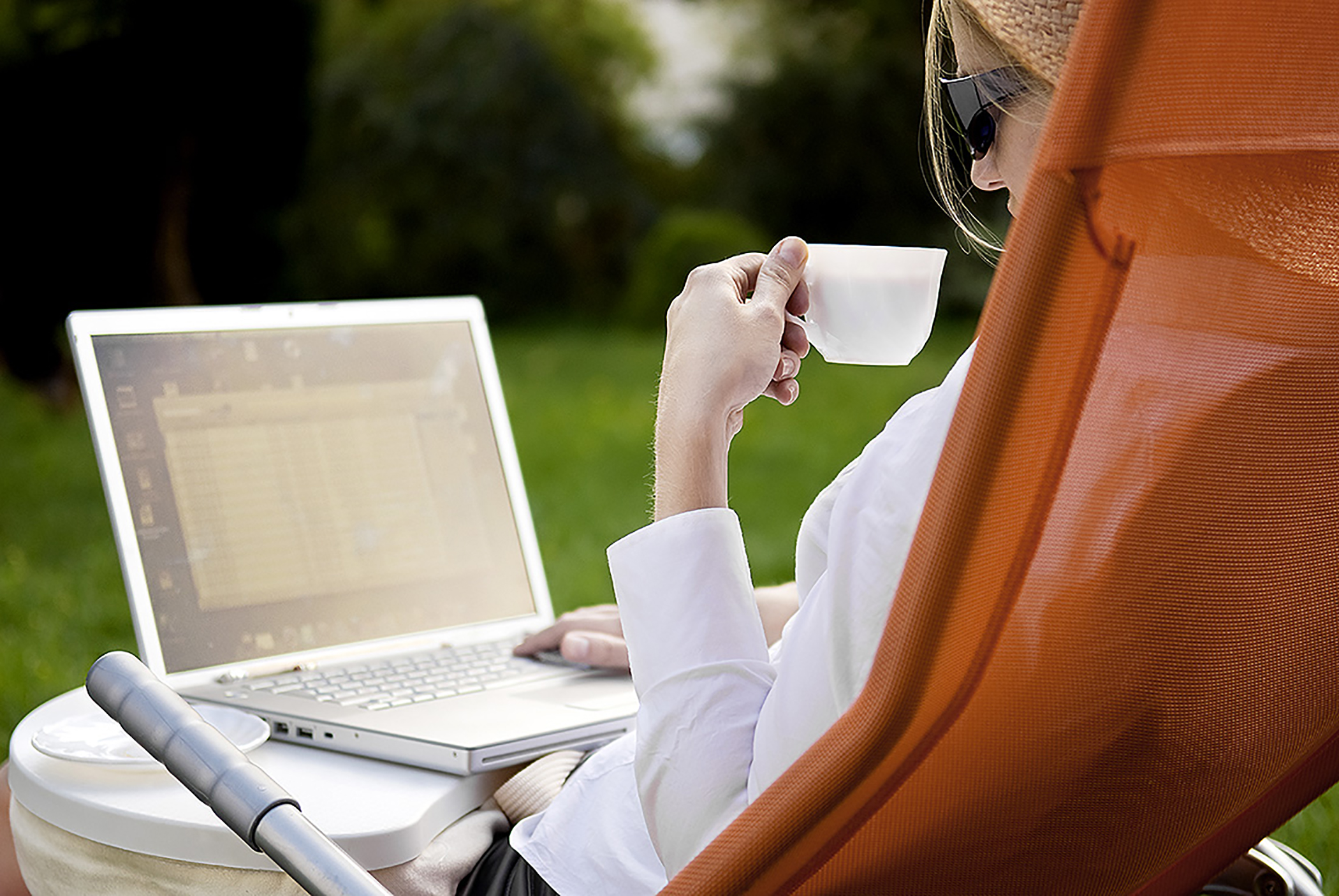 Young woman working outside on computer and drinking coffee